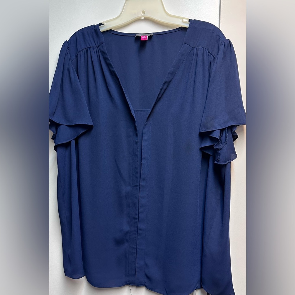 Navy short sleeve blouse with feminine details at sleeves and shoulders.